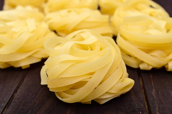 Pasta tagliatelle i form av Bon på den mörka bakgrunden. Närbild. — Stockfoto