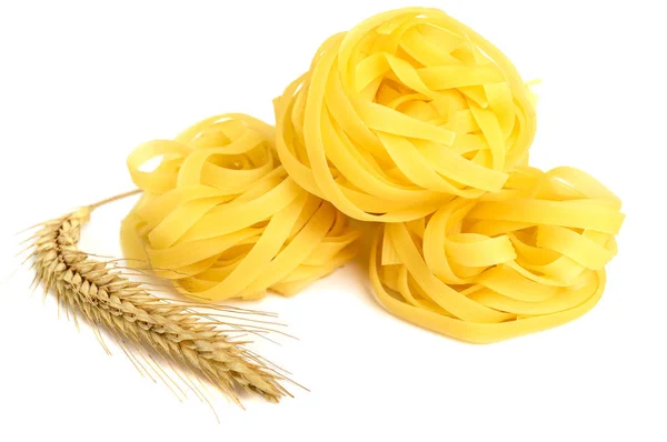 Tagliatelle di pasta in un nido e spikelet di grano isolato su fondo bianco. Primo piano . — Foto Stock