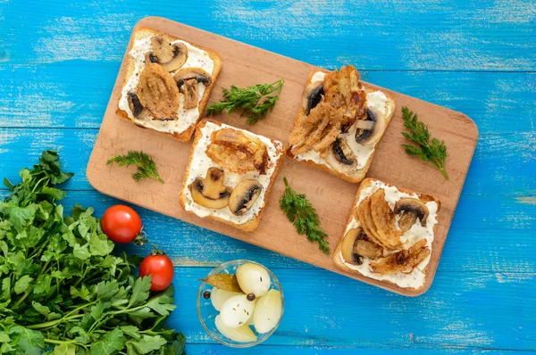 Crispy tosty biały chleb w kształcie kwadratu z pieczarkami, cebulą, frytki, sos tatarski na pokładzie cięcia na niebieskim tle drewnianych. — Zdjęcie stockowe