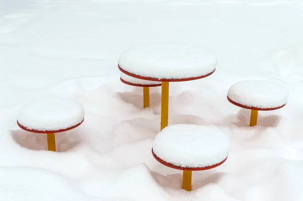 Sneeuw bedekte Kinder tafel en banken. Sneeuw caps op baby schommel. Close-up. Winterlandschap. — Stockfoto