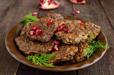 Nar tohumları koyu ahşap arka plan üzerinde seramik plaka ile sulu karaciğer pirzola.