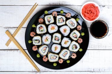 Somon suşi ile geleneksel Doğu çanak siyah bir plaka üzerinde rulo. Üstten Görünüm