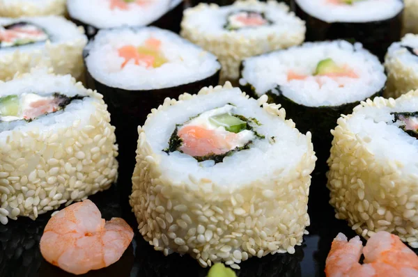 Traditionell östra maträtt med lax sushi rullar på en svart plåt. — Stockfoto