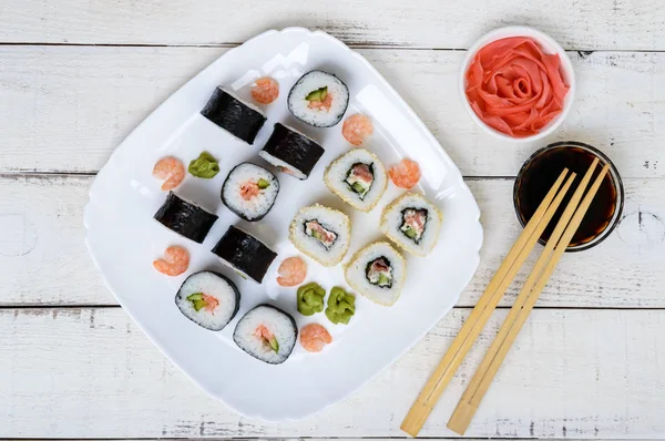 Traditionell östra maträtt - sushi rullar med lax och räkor på en vit platta. Ovanifrån — Stockfoto