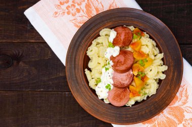 Galetti makarna adet sosis, koyu ahşap arka plan üzerinde sarı domates ve kremsi hardal sosu bir kil kase. Üstten Görünüm