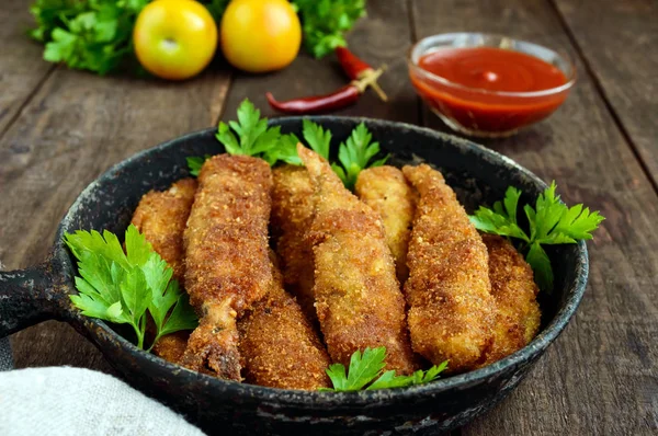 Freír un pequeño capelán de pescado en una sartén sobre un fondo de madera oscura. Buena merienda a la cerveza . —  Fotos de Stock