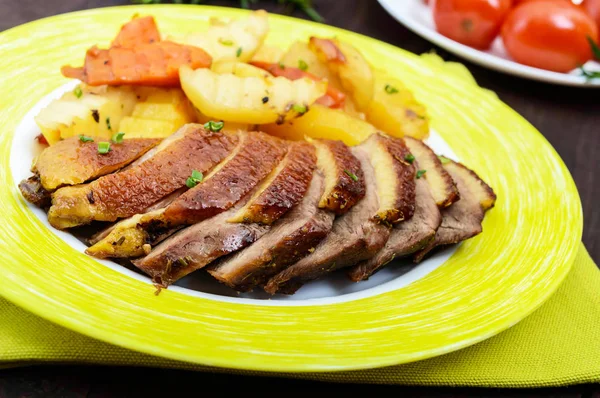 Filete de pechuga de ganso asado con papas de estilo rústico en un plato sobre un fondo de madera oscura. De cerca. — Foto de Stock