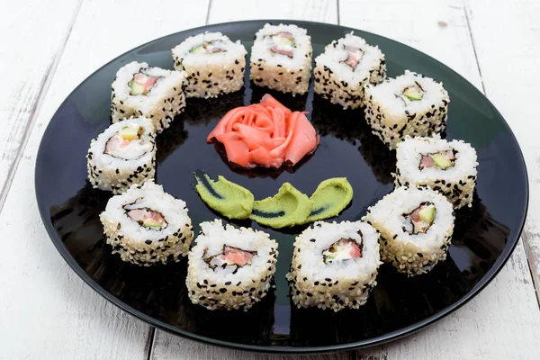 Piatto orientale tradizionale con salmone, gamberetti - rotoli di sushi su un piatto nero . — Foto Stock