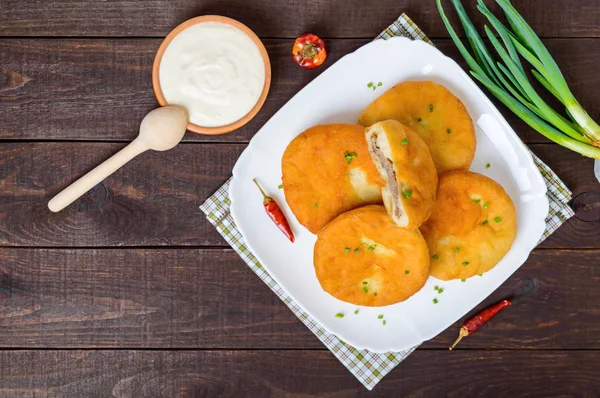 Frittierte Pasteten mit Fleisch auf einem weißen Teller mit saurer Sahne — Stockfoto