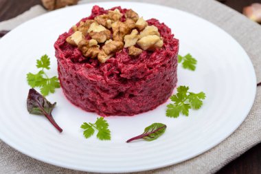 Vejetaryen Lenten yemek: ceviz ve koyu ahşap arka plan üzerinde bir daire şeklinde beyaz bir tabak içinde sarımsak pancar salatası. Yakın çekim