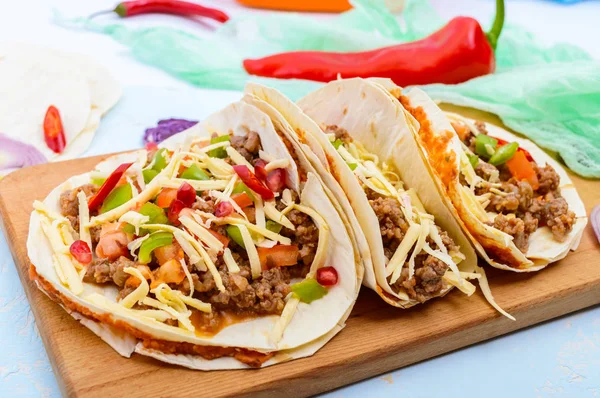 Taco pedas Meksiko dengan daging cincang, kacang tumbuk, sayuran, keju parut . — Stok Foto