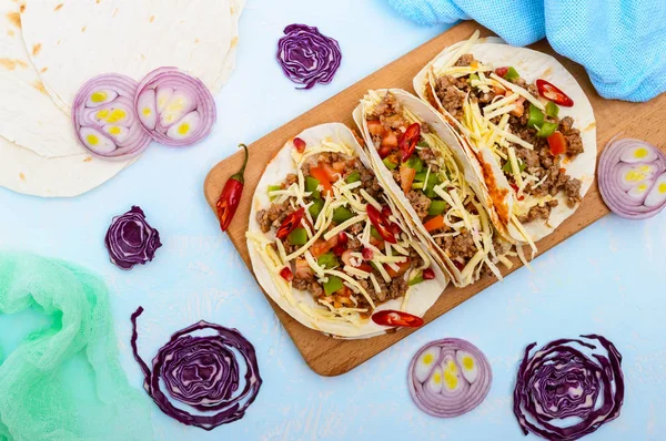 Tacos mexicanos picantes con carne picada, puré de frijoles, verduras, queso rallado. La vista superior —  Fotos de Stock