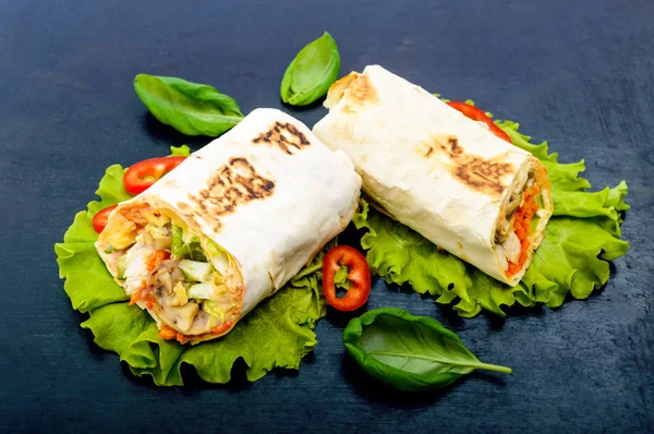 Shawarma - Plato de Oriente Medio hecho de lavash (pita), relleno de pollo, champiñones, ensalada de verduras frescas, salsa. Servir sobre hojas de lechuga sobre fondo negro . —  Fotos de Stock