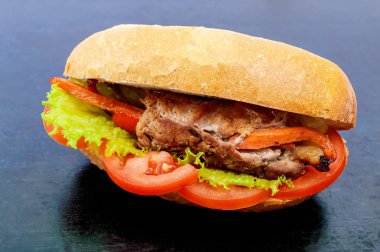 Sandviç: Et ile sebze domates ile bir topuz olarak alır ve siyah arka plan üzerine marul yaprakları.