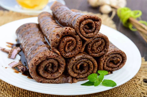 Thin delicate chocolate pancakes, rolled, laid out in a pile — Stock Photo, Image