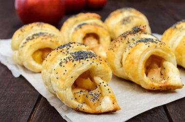 Ay çöreği (simit) ile elma, koyu ahşap arka plan üzerinde haşhaş tohumu ile dekore edilmiş ev yapımı.