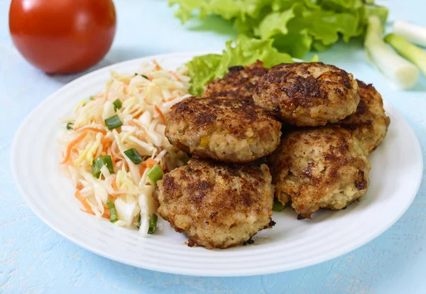 Costeletas suculentas e salada com verduras frescas: repolho, cenouras, verdes em uma chapa branca . — Fotografia de Stock