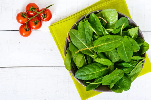 Daun hijau muda sorrel (bayam) dalam mangkuk keramik dalam tetesan air, di latar belakang kayu putih. Tampilan atas — Stok Foto