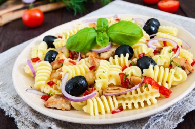 Makarna salatası radiatori tavuk, tatlı biber koyu ahşap arka plan üzerinde siyah zeytin, mavi soğan ile.