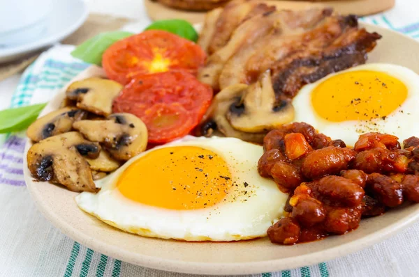 Desayuno inglés: huevos, tocino, frijoles en salsa de tomate, champiñones, tomates, tostadas con queso crema — Foto de Stock