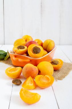 beyaz zemin üzerinde bir seramik kase olgun kayısı.