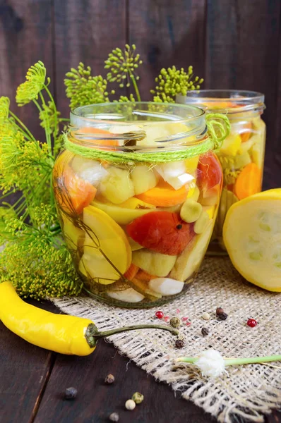 Pickles : assortiment de légumes (courgettes, poivre, carottes, tomate, pois verts) dans des bocaux en verre sur fond bois foncé . — Photo