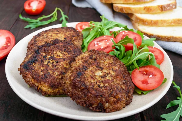 Chuletas jugosas en un plato con una ensalada de tomates y rúcula —  Fotos de Stock