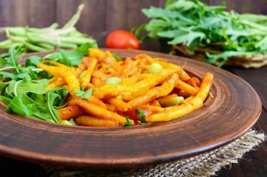 Roka yeşil fasulye, domates sosu ve yeşil soğan ile demlenmiş üzerinden salata yaprakları 