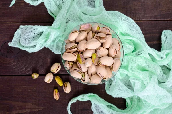 Pistachio nuts in a bowl on a dark wooden background — Stock Photo, Image