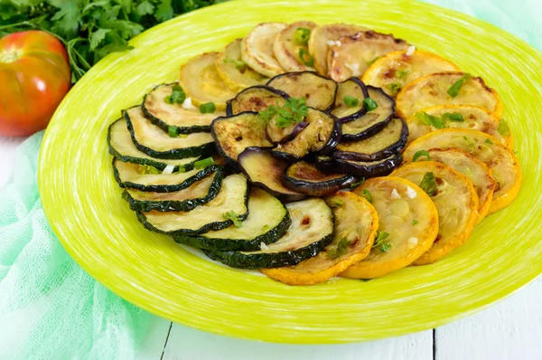 Kabak, patlıcan bir plaka üzerinde beyaz bir arka plan üzerinde kızarmış çevreler. Vejetaryen mutfağı.