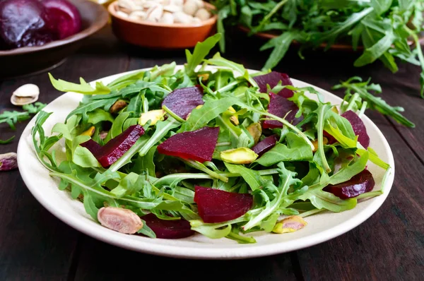 Vegan sebze vitamini salata pancar, roka ve koyu ahşap zemin üzerine Antep fıstığı. — Stok fotoğraf