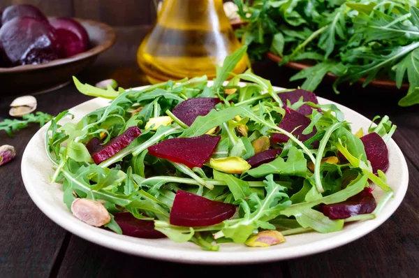 Vegan sebze vitamini salata pancar, roka ve koyu ahşap zemin üzerine Antep fıstığı. — Stok fotoğraf
