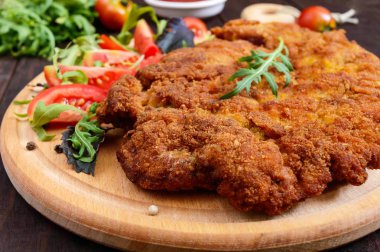 Koyu ahşap arka plan üzerinde büyük bir Viyana şnitzel.