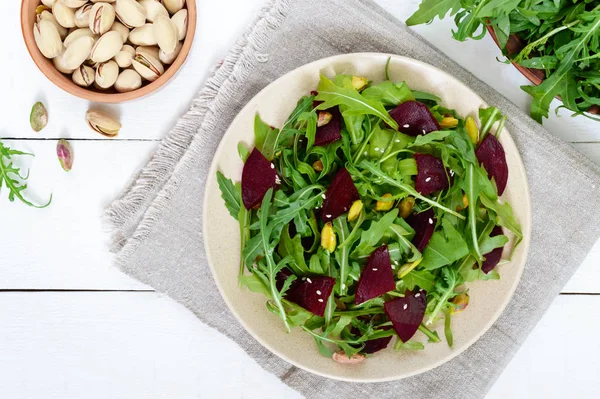 Spicy vegan salad of beets, arugula, pistachio nuts on a plate — Stock Photo, Image