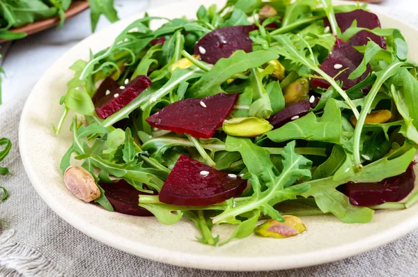 Spicy vegan salad of beets, arugula, pistachio nuts on a plate on a white background. — Stock Photo, Image