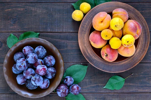 Olgun Erik ve koyu ahşap arka plan üzerinde seramik kase kayısı. Üstten Görünüm.