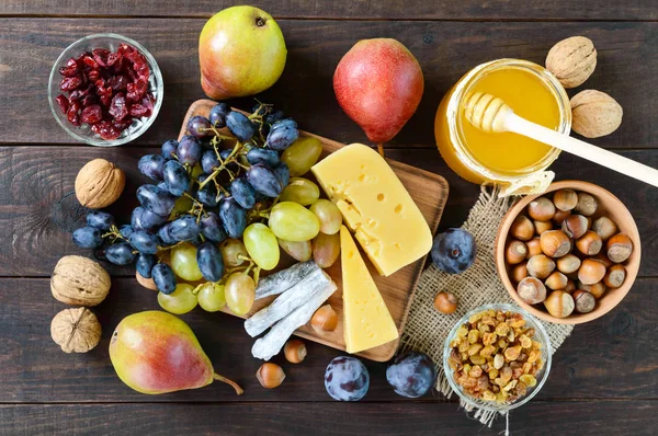Sonbahar dizi: üzüm, ceviz, fındık, Erik, bal, peynir, Kuru üzüm, armut, kurutulmuş cranberries ahşap arka plan üzerinde. 