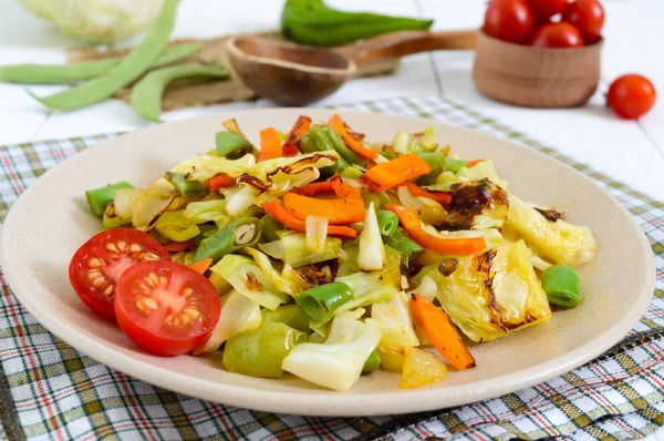 Рагу из овощей - смесь выпечки капусты, зеленой фасоли, лука, моркови, помидоров черри, сладкого перца на тарелке на белом деревянном фоне . — стоковое фото
