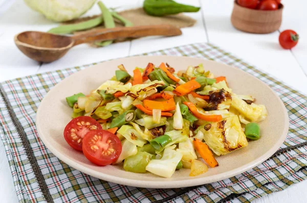 Sebze Güveç - fırında lahana, yeşil fasulye, soğan, havuç, domates, Beyaz ahşap zemin üzerinde bir tabakta tatlı biber karışımı. 