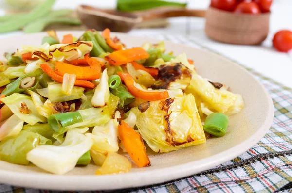 Sebze Güveç - fırında lahana, yeşil fasulye, soğan, havuç, domates, Beyaz ahşap zemin üzerinde bir tabakta tatlı biber karışımı. 