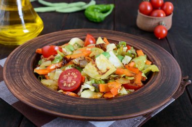 Lahana, yeşil fasulye, havuç, domates, soğan, koyu ahşap arka plan üzerinde bir kil kase içinde tatlı biber, sebze güveç. Sıcak salata.