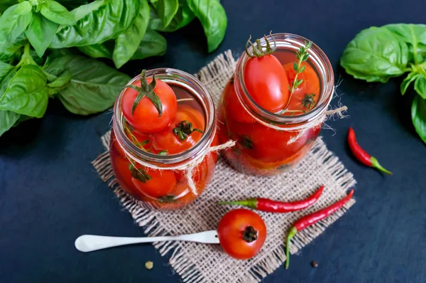 Zure tomaten in een glazen pot op een zwarte achtergrond. Augurken — Stockfoto