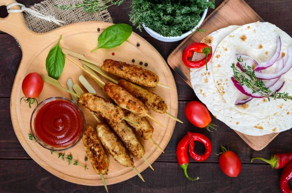 Lula Kebab ist ein traditionelles kaukasisches Gericht. Hackfleisch mit Spießen. Servieren mit Lavasch, Tomatensauce auf einem Holzbrett auf dunklem Hintergrund. — Stockfoto