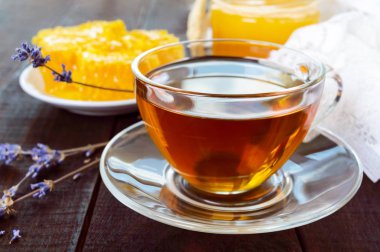 Bir fincan çay ve koyu ahşap bir masa üzerinde petek.