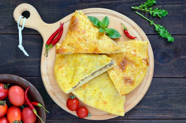 Khachapuri mit Fleisch - traditionelles georgisches Gebäck auf einem dunklen Holztisch. Ansicht von oben. — Stockfoto