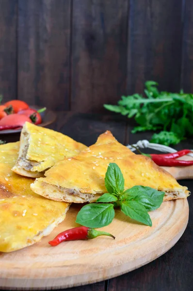 Khachapuri with meat - traditional Georgian pastry on a dark wooden table. — Stock Photo, Image