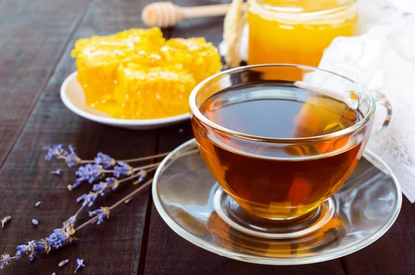 Bir fincan çay ve koyu ahşap bir masa üzerinde petek.