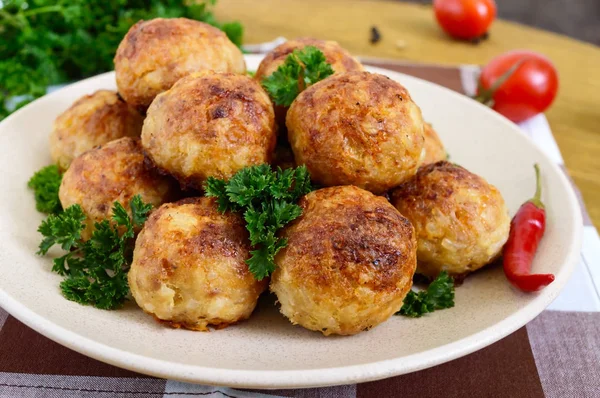 Une pile de boulettes de viande dorée sur une assiette avec du persil sur une table en bois . — Photo