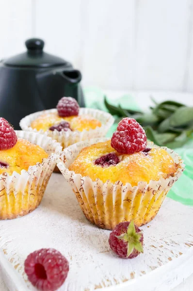 Deliziosi muffin appena sfornati con lamponi, decorati con zucchero a velo — Foto Stock