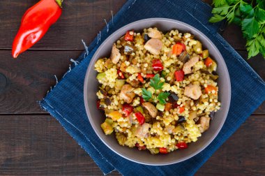 Kuskus, sebze (kabak, patlıcan, havuç, tatlı biber, soğan), koyu ahşap arka plan üzerinde tavuk parçaları ile hafif sağlıklı diyet salata.